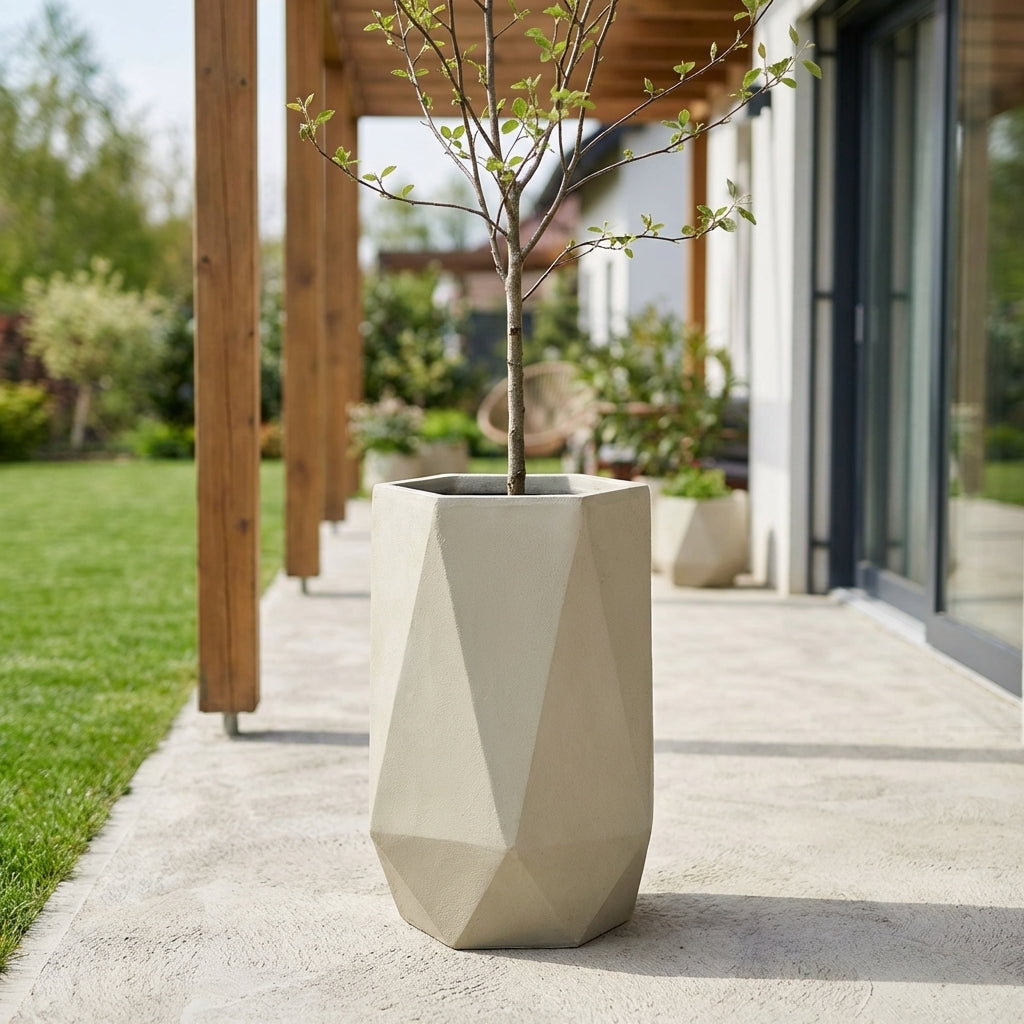 Detailní záběr na betonový květináč PRISME v béžové barvě se stálezeleným keřem na moderní prosluněné terase.